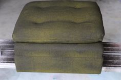 a green ottoman sitting on top of a wooden bench