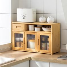 a wooden cabinet with glass doors on top of it next to a white microwave oven