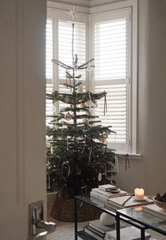 a small christmas tree sitting in the corner of a room next to a window with shutters