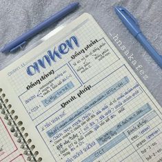 an open notebook sitting on top of a bed next to a blue pen and paper