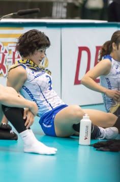 two women sitting on the floor in volleyball uniforms