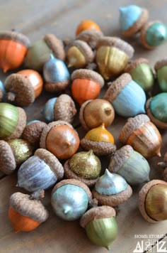 a bunch of different colored acorns sitting on top of a wooden table next to each other