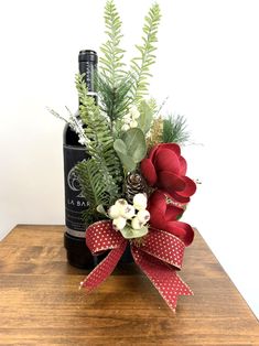 a bottle of wine sitting on top of a wooden table next to a flower arrangement