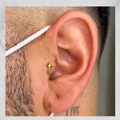 a man's ear with a tiny yellow cross on it