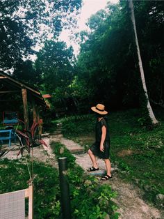 a woman wearing a straw hat walking down a path