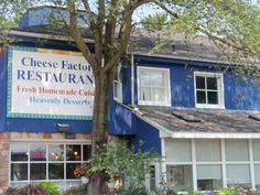 the cheese factory restaurant is located in front of a blue building with white trim and windows