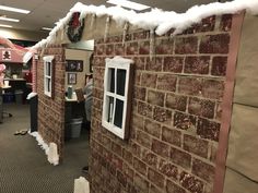 an office cubicle decorated for christmas with snow on the roof and windows, along with people working at desks