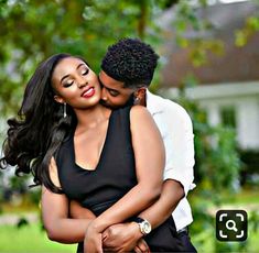 a man and woman embracing each other in front of trees