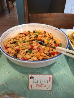 a bowl filled with pasta and vegetables on top of a table next to other dishes