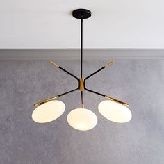 three lights hanging from a ceiling fixture in a room with concrete walls and flooring