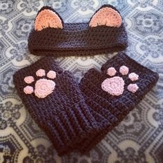 two crocheted mittens with paw prints on them sitting on a patterned surface