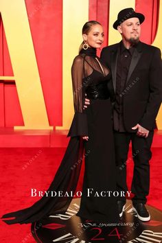 a man and woman in black outfits standing on a red carpet at the oscars