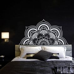 a black and white bedroom with an intricate wall decal on the headboard,