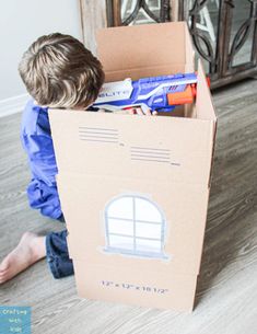 a young boy sitting on the floor in a cardboard box