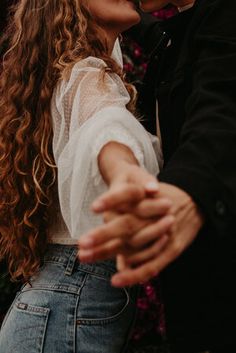 a man and woman kissing in front of flowers