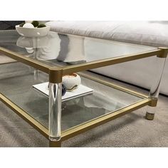 a glass coffee table sitting on top of a carpeted floor next to a white couch