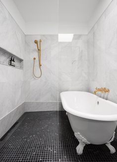 a white bath tub sitting in a bathroom next to a shower head and hand held faucet