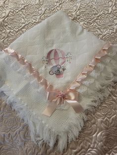 a white blanket with a pink bow on it and a monogrammed hot air balloon