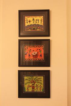 three framed pictures hang on the wall above a toilet