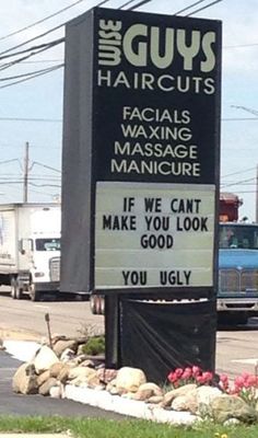 the guy's haircuts sign is in front of some trucks and flowers