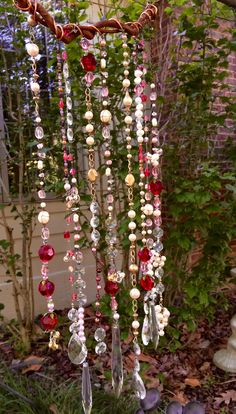 a wind chime hanging from a tree with beads and pearls on it's chains