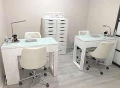 a white desk with two chairs and a mirror in a room that has drawers on the wall