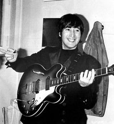 a black and white photo of a young man holding an electric guitar