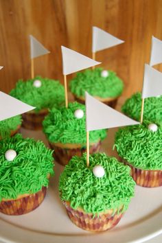 cupcakes with green frosting and white flags on top are sitting on a plate