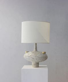 a table lamp sitting on top of a white block with a light shade over it