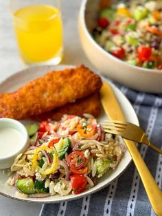 a white plate topped with rice and vegetables next to a bowl of salad on top of a table