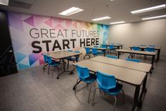 an empty classroom with desks and chairs in front of a wall that reads great futures start here