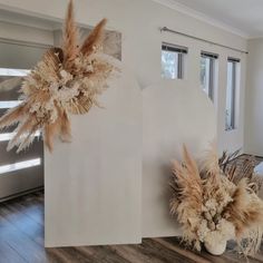 two fake flowers are placed next to a white board in a room with wood floors