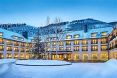 the hotel is covered in snow and lit up at night with mountains in the background