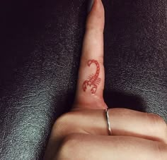 a person's finger with a tattoo on it that has the letter c in red ink