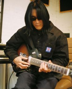 a man with long black hair is playing an electric guitar