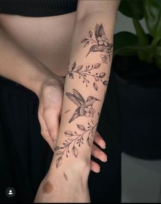 a woman's arm with flowers and birds on it