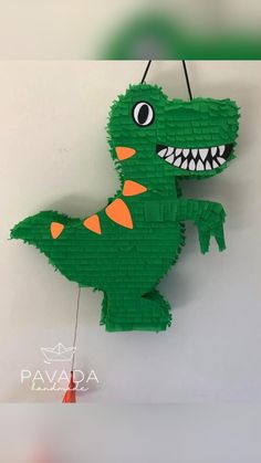 a paper cut out of a green dinosaur hanging from a hook on a wall with the words pavara above it