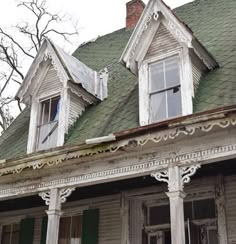 an old house with green roof and white trim