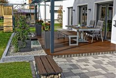 an outdoor dining area with table, chairs and potted plants on the decking