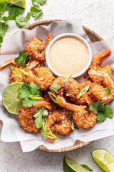 a plate filled with shrimp and garnished with cilantro, lime wedges and a small bowl of dipping sauce