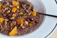 a bowl filled with fruit and nuts on top of a white plate next to a spoon