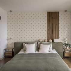 a large bed sitting in a bedroom next to a wooden table and lamp on top of a hard wood floor