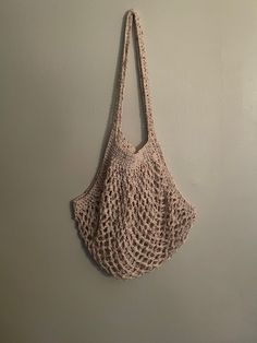 a crocheted bag hanging on the wall in front of a white wall,