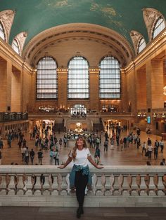 a woman is standing in the middle of a train station