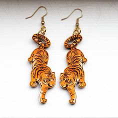 "Take a walk on the wild side with these laser engraved tiger 🐯 earrings. Each pair is hand-painted and laser engraved on both sides. They are made of 1/8\" baltic birch with your choice of silver, gold, or antique brass hypo allergenic nickel free earring hooks.  Tigers are 2.2 inches in length and with hardware hang close to 3 inches. They can be made slightly smaller or larger by request. To ensure your earrings retain their beauty, avoid wearing them in water." Tiger Earrings, Laser Cut Earrings, Hand Painted Earrings, Cut Earrings, Walk On The Wild Side, Painted Earrings, Nickel Free Earrings, Take A Walk, Wooden Earrings