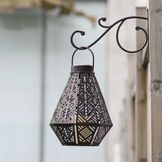 a lantern hanging from the side of a wooden fence with an intricate design on it