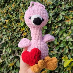 a hand holding a pink crocheted stuffed animal with a heart