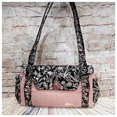 a black and pink purse sitting on top of a wooden table next to a brick wall