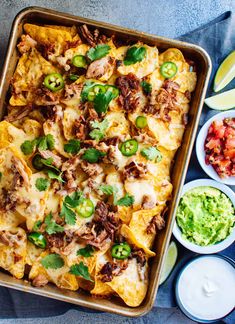 a casserole dish with tortilla shells, salsa and guacamole