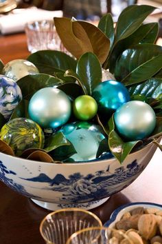 a bowl filled with ornaments sitting on top of a table next to other dishes and cups